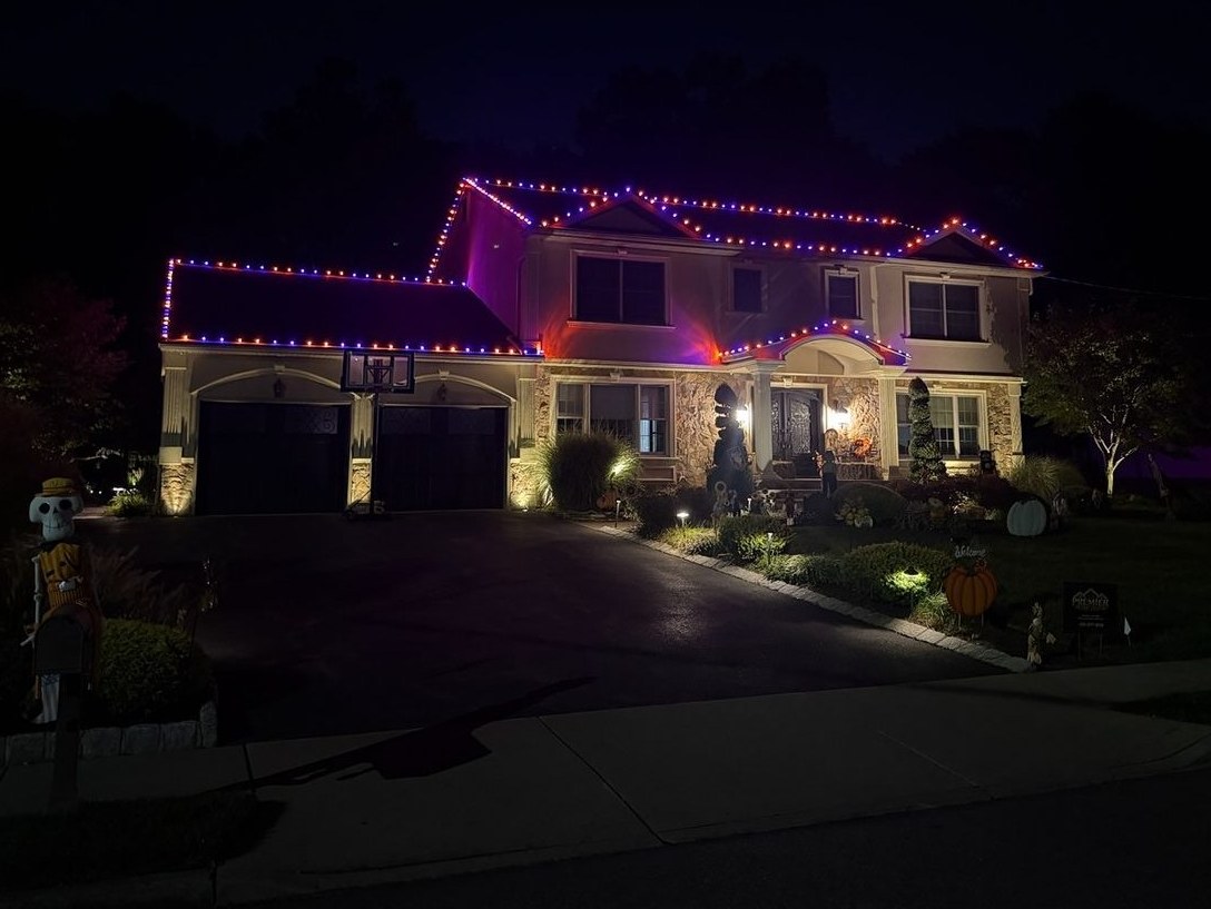 Two-story home with orange and purple Halloween lights along every roofline